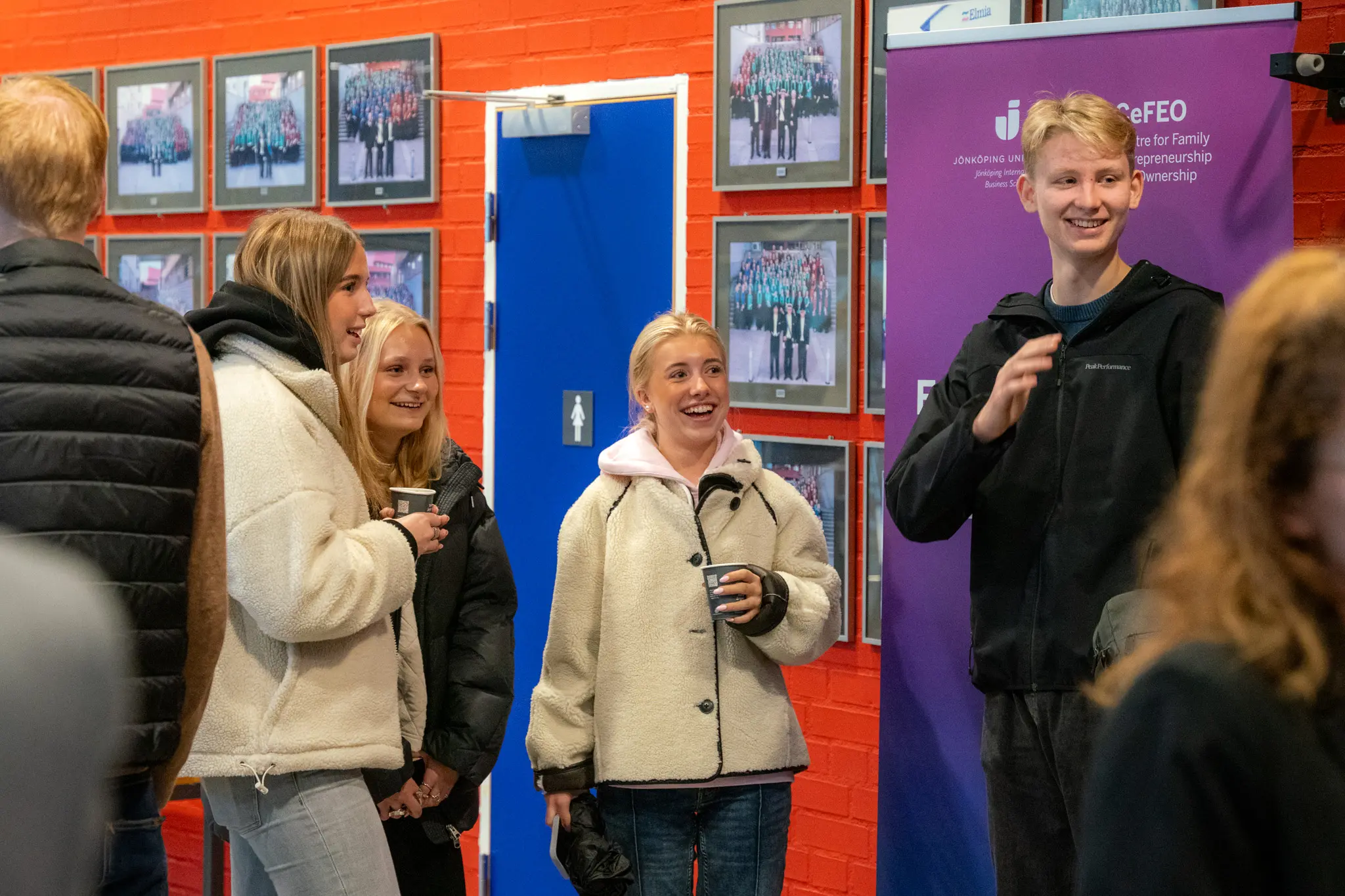 En grupp gymnasieelever ler och hälsar mot någon.